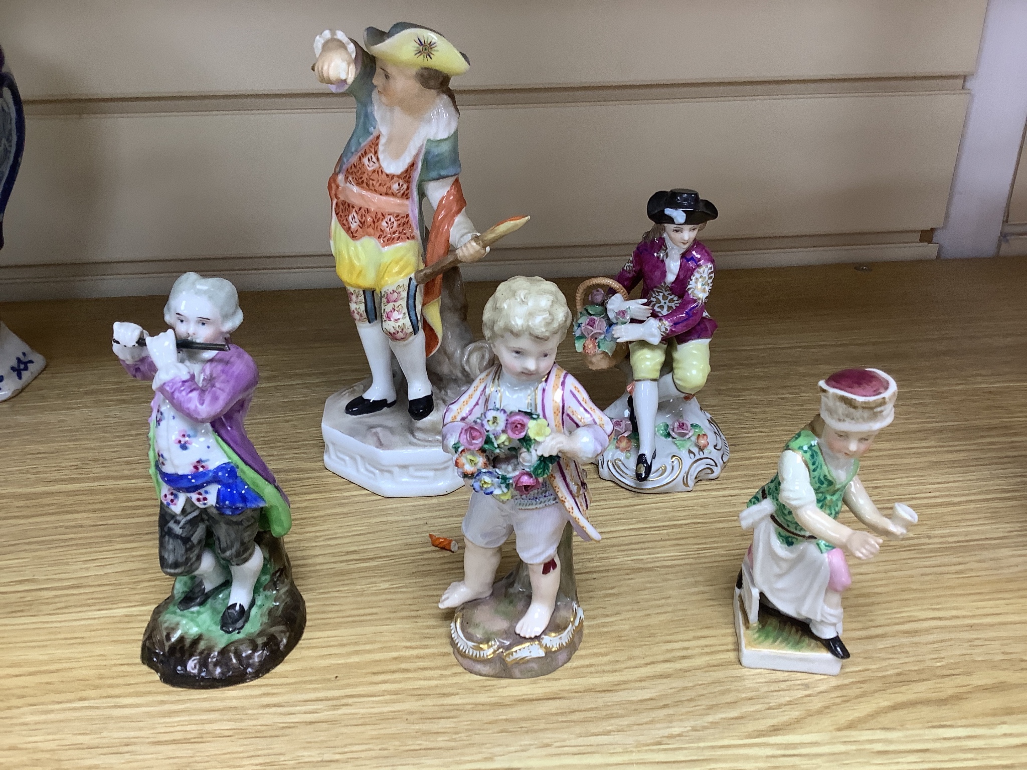 A late 19th century Meissen figure of a boy holding a garland of flowers, and a Sampson Hancock Derby figure and three other continental porcelain figures, tallest 18 cms high.